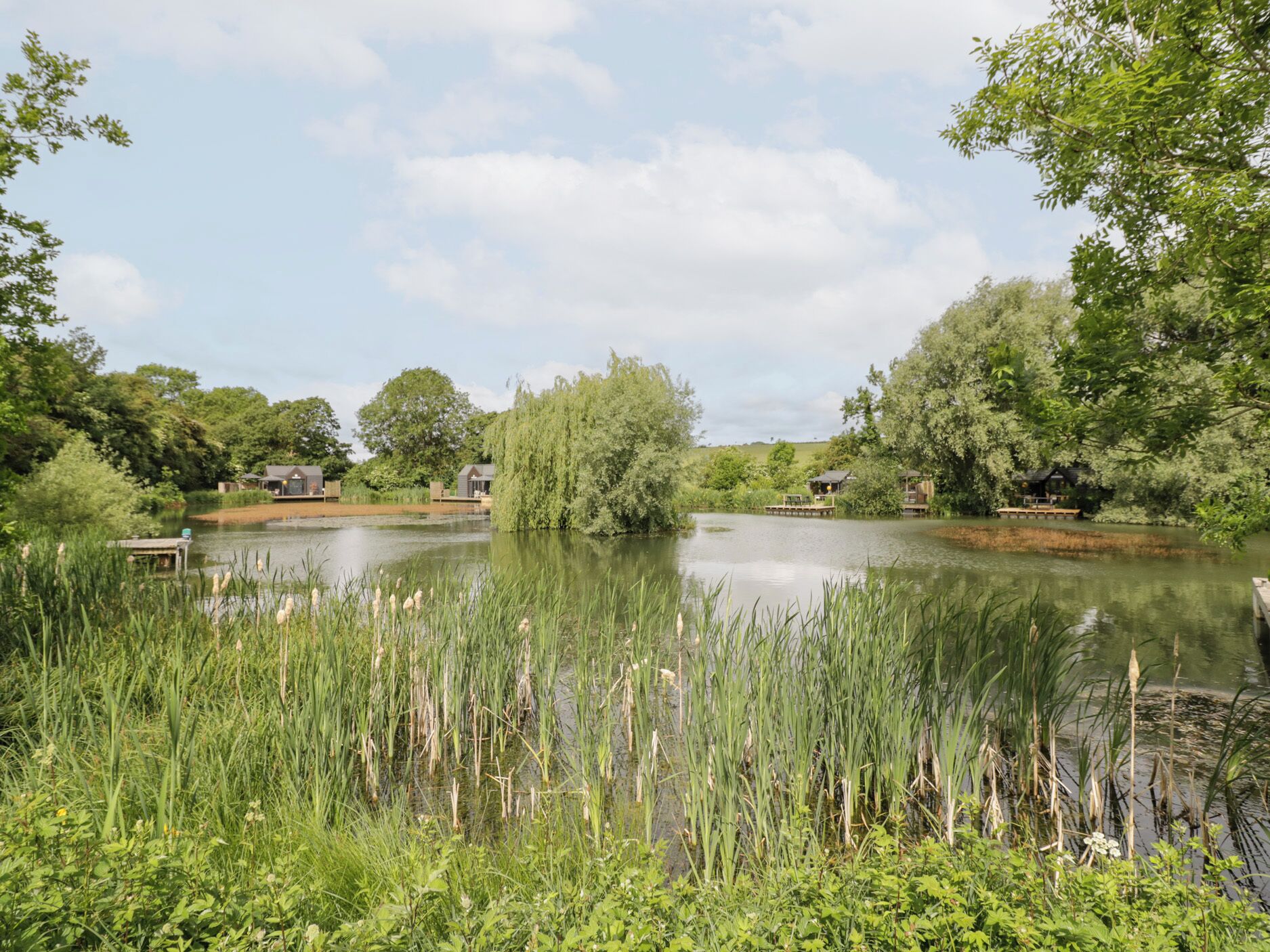 A serene lakeside setting with wooden docks and houses surrounded by lush greenery and trees.