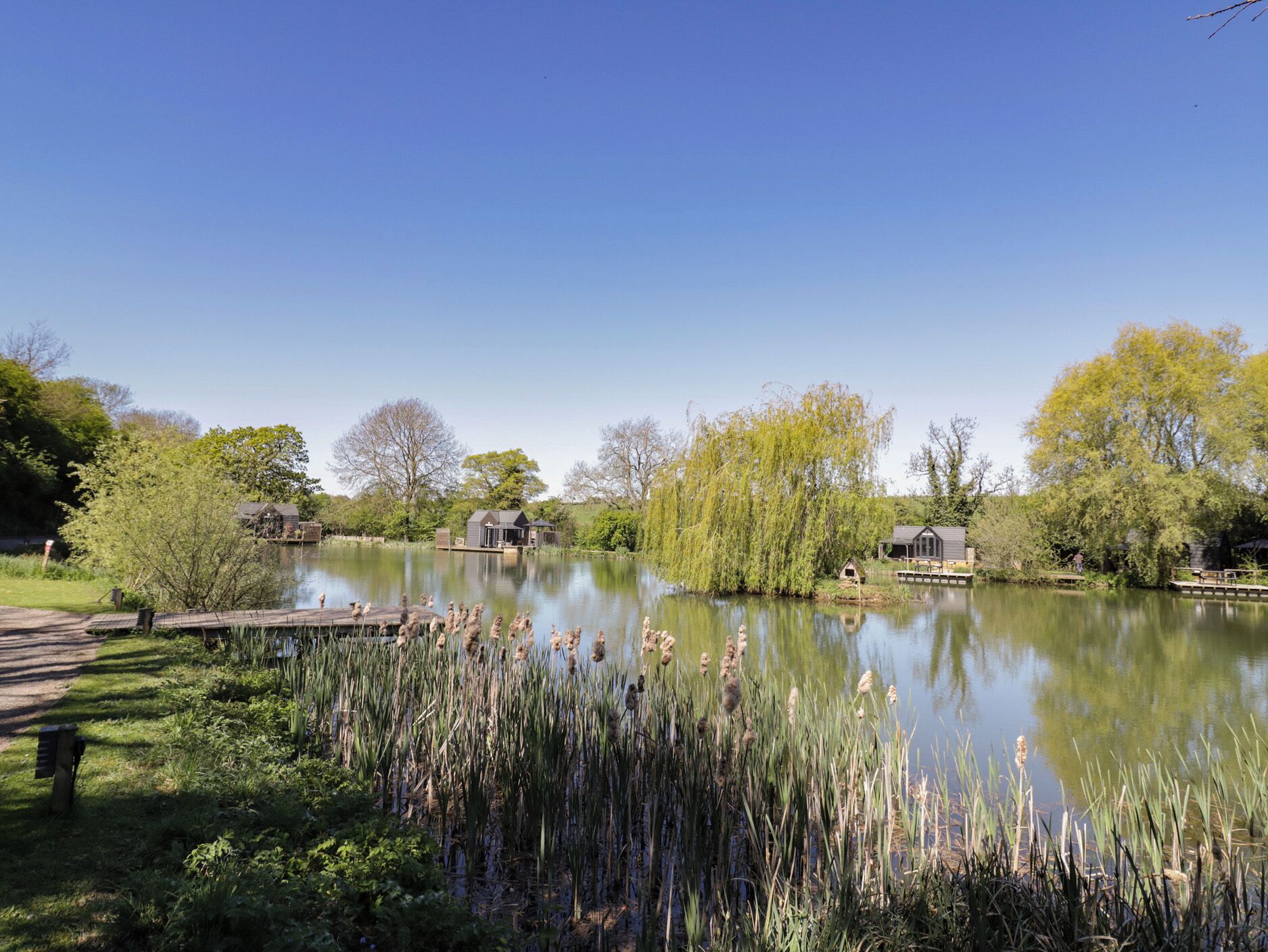 A tranquil lakeside setting with a dock, wooden structures, and lush greenery.