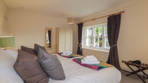 A hotel room with a large bed, a wardrobe, a window with curtains, and a radiator. - Inverewe - Garden Lodge (Achnasheen)