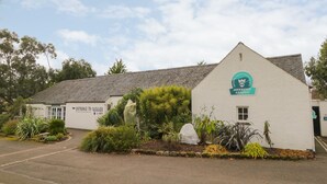 A building with a sign reading "Entrance to Garden" and "National Trust Property Invervegan." - Inverewe - Garden Lodge (Achnasheen)