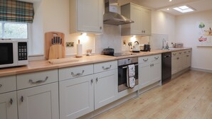 A modern kitchen with white cabinets, a microwave, a toaster, and a kettle. - Inverewe - Garden Lodge (Achnasheen)