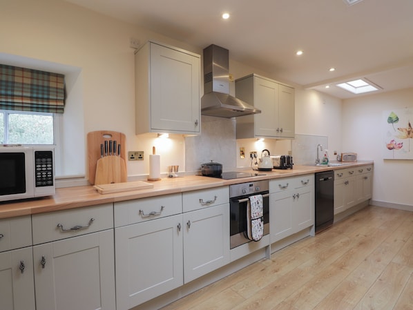 A modern kitchen with white cabinets, a microwave, a toaster, and a kettle.