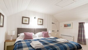 Un dormitorio con una cama, dos mesitas de noche, un radiador y una puerta.