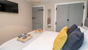 Un dormitorio con cama, televisor, armario y espejo.