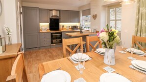 Una cocina moderna con gabinetes grises, una mesa de comedor de madera para seis personas y un florero con flores sobre la mesa.