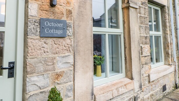Un edificio de piedra con un cartel que dice "October Cottage".