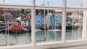 A harbor view through a window with boats, colorful buildings, and a clear sky. - Seasides (Weymouth)