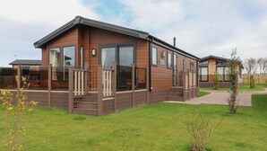 En moderne mobilhome med træfacade, store vinduer og en overdækket veranda.