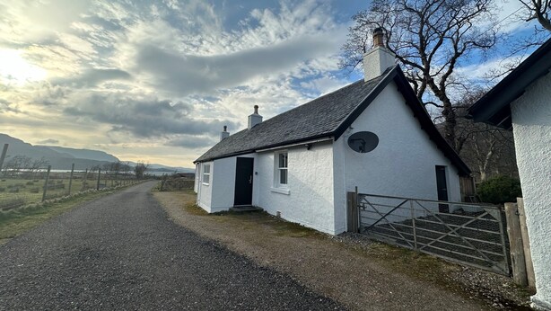 A white cottage with a black door, a chimney, and a fenced yard. - Stalker's Cottage - Torridon (Achnasheen)