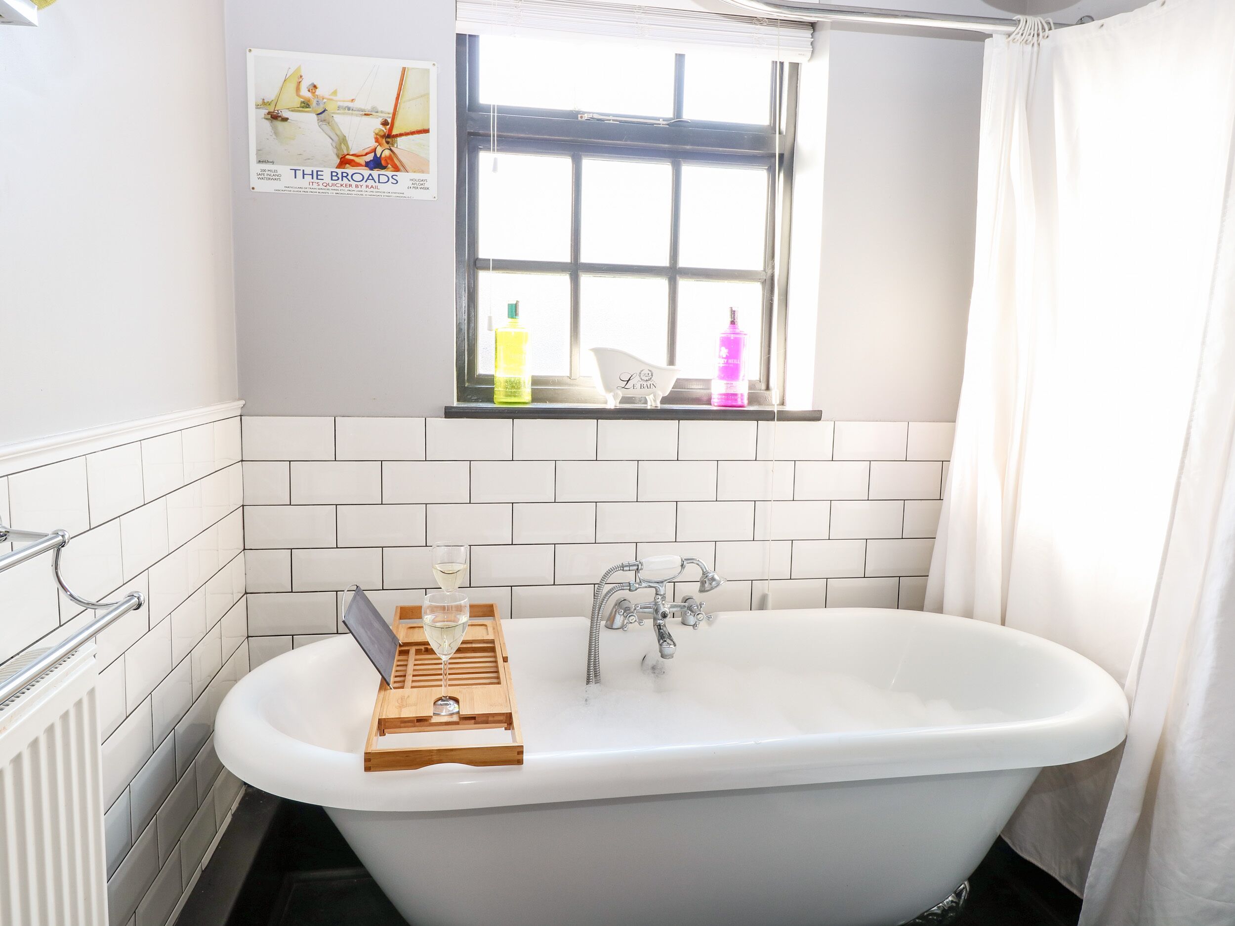 A bathroom with a freestanding bathtub, a window with a view, and a towel rack.