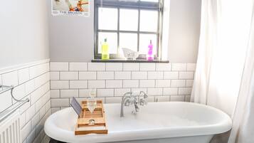 A bathroom with a freestanding bathtub, a window with a view, and a towel rack.