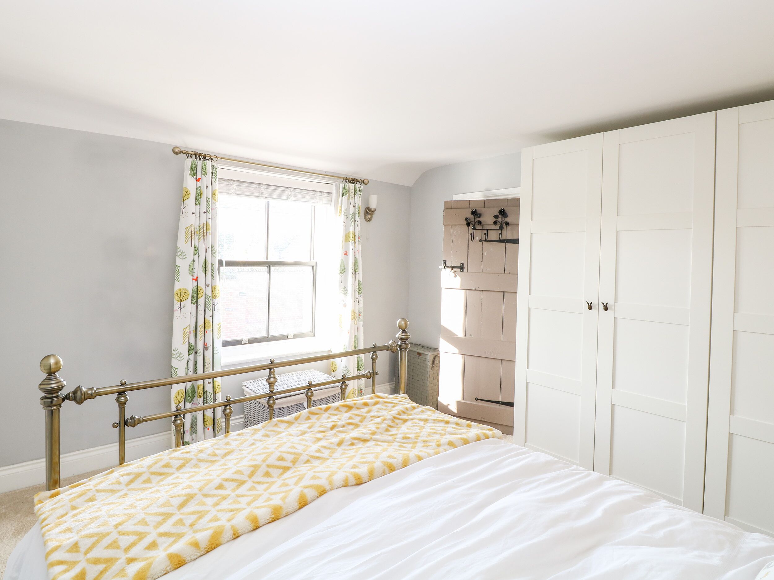 Un dormitorio con cama, ventana con cortinas, armario y radiador.