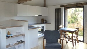 Una cucina moderna con mobili bianchi, forno integrato e zona pranzo con tavolo blu e sedie di legno.