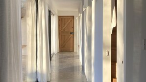 A corridor with white walls and a wooden door at the end. - High Cogges Farm Holiday Cottages The Cart Shed (Witney)