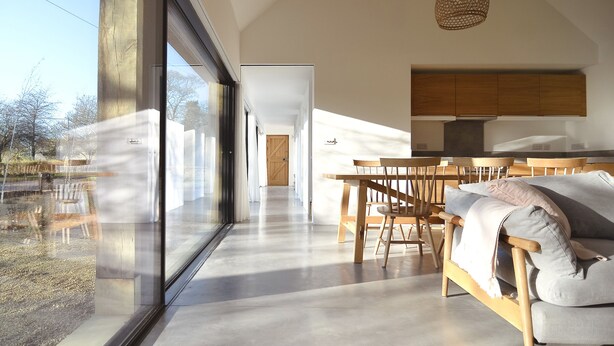 A modern interior with a large window, a dining area with wooden furniture, and a kitchen with wooden cabinets. - High Cogges Farm Holiday Cottages The Cart Shed (Witney)