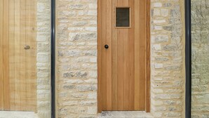 A wooden door with a small window, set in a stone wall with a rounded arch above it. - High Cogges Farm Holiday Cottages The Cart Shed (Witney)