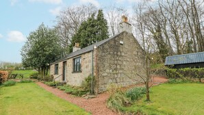 A stone house with a sloped roof, a chimney, and a small porch. - Beechgrove Cottage - Pitmedden Gardens (Ellon)