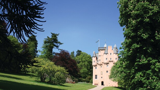 A castle with a paved pathway leading to its entrance, surrounded by lush greenery and trees. - Steading Cottage - Craigievar Castle (Alford)