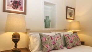 A bedroom with a bed, two nightstands, two lamps, a vase, and two framed pictures on the wall. - Steading Cottage - Craigievar Castle (Alford)