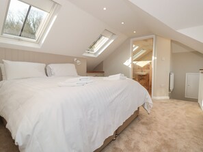 Une chambre à coucher avec un grand lit, des fenêtres de toit, un dressing et une salle de bain.
