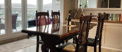 A dining area with a glass-top table, wooden chairs, and a telescope on a tripod.