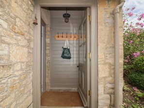 Une entrée aux murs de pierre, dotée d’une porte en bois, d’un porte-manteau suspendu et d’un paillasson.
