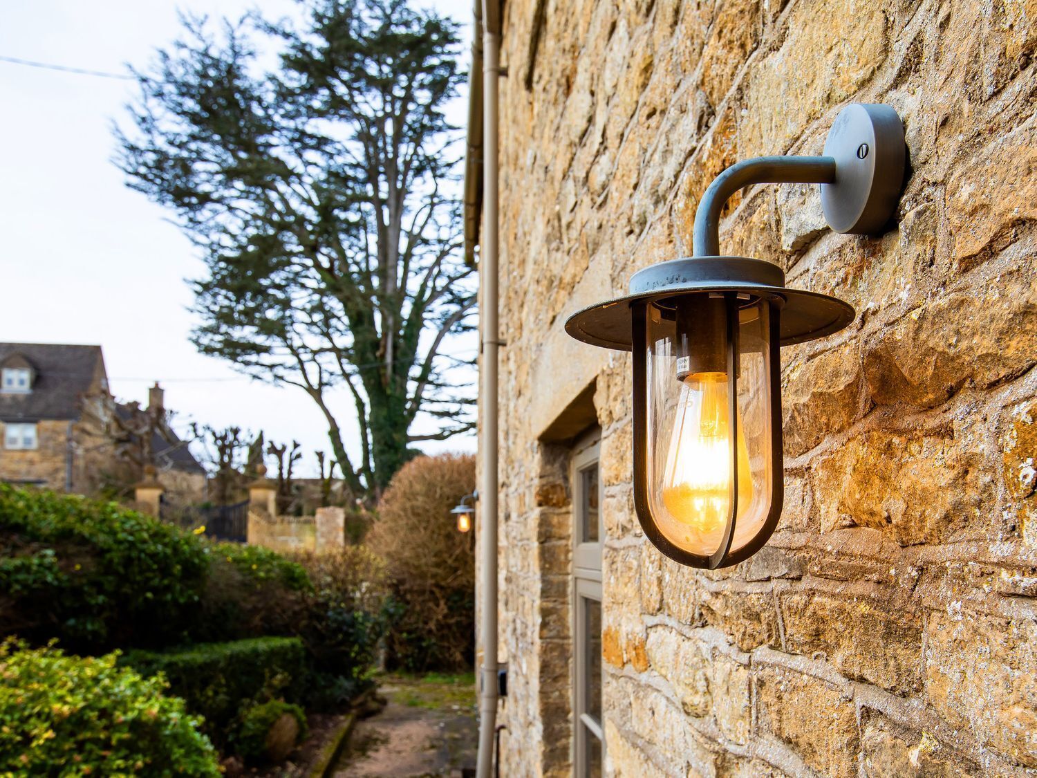 A stone wall with a mounted lantern-style light fixture.