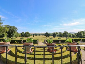 A landscaped garden with a series of terraced flower beds and a distant view of rolling hills. - North Stables - House Of Dun (Montrose)