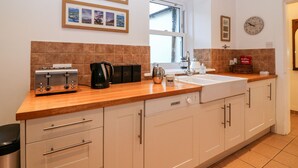 Une cuisine avec un plan de travail en bois, une machine à café, un grille-pain, un évier et une fenêtre.
