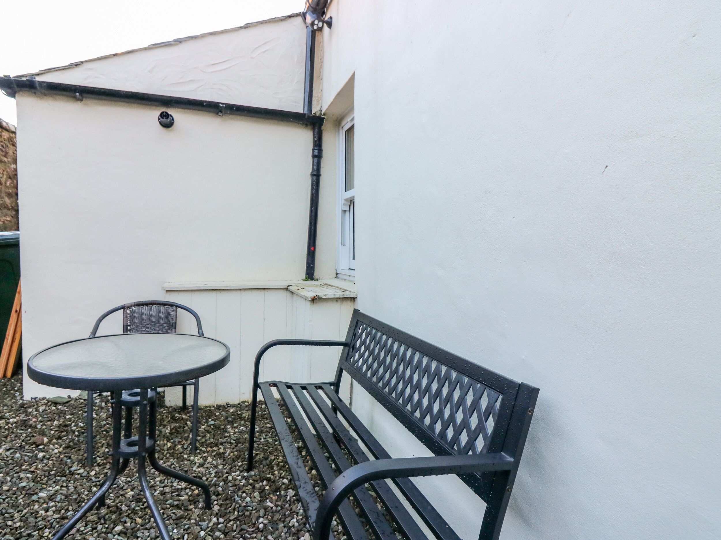 Un petit espace extérieur aménagé avec une table et un banc en métal, entouré de galets.