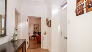 Un couloir avec une commode en bois, une chaise rouge et une porte blanche.
