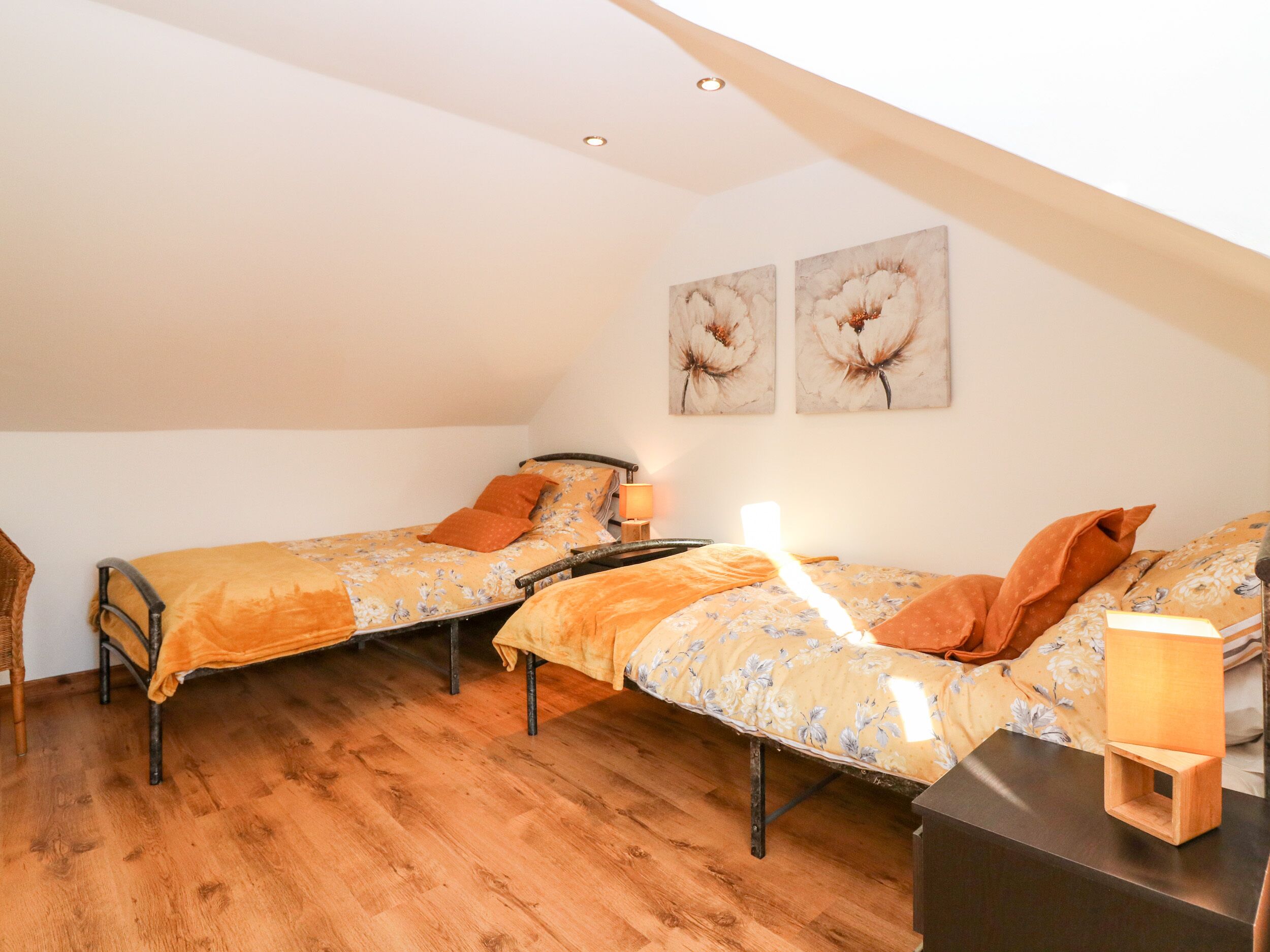Un dormitorio acogedor con dos camas individuales, suelo de madera y techo inclinado.