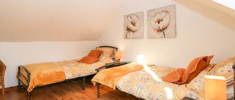 Un dormitorio acogedor con dos camas individuales, suelo de madera y techo inclinado.