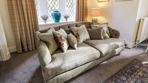A cozy living room with a sofa, decorative pillows, a vase, and a lamp. - East Lodge - Crathes Castle (Banchory)