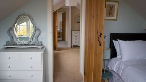 Une chambre à coucher comprenant un lit, une commode, un miroir et une porte donnant sur une autre pièce.