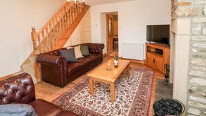 A living room with a brown leather sofa, a wooden coffee table, a TV stand, and a fireplace. - Bolt's View (Bishop Auckland)
