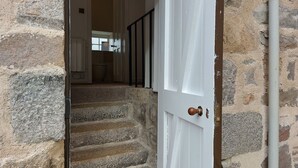 Una escalera de piedra conduce a una habitación con una puerta blanca y una barandilla negra.