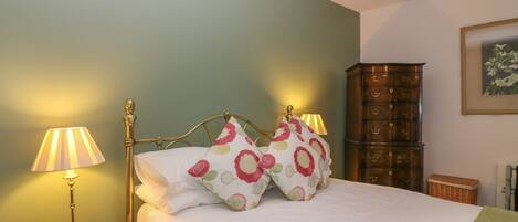 Une chambre à coucher avec un lit, deux lampes de chevet, une commode et un tableau au mur.