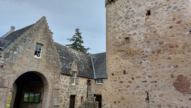 Un edificio histórico de piedra con una torre, una entrada en arco y una ventana pequeña.