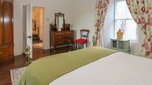 Un dormitorio con cama, cómoda, silla y ventana con cortinas.