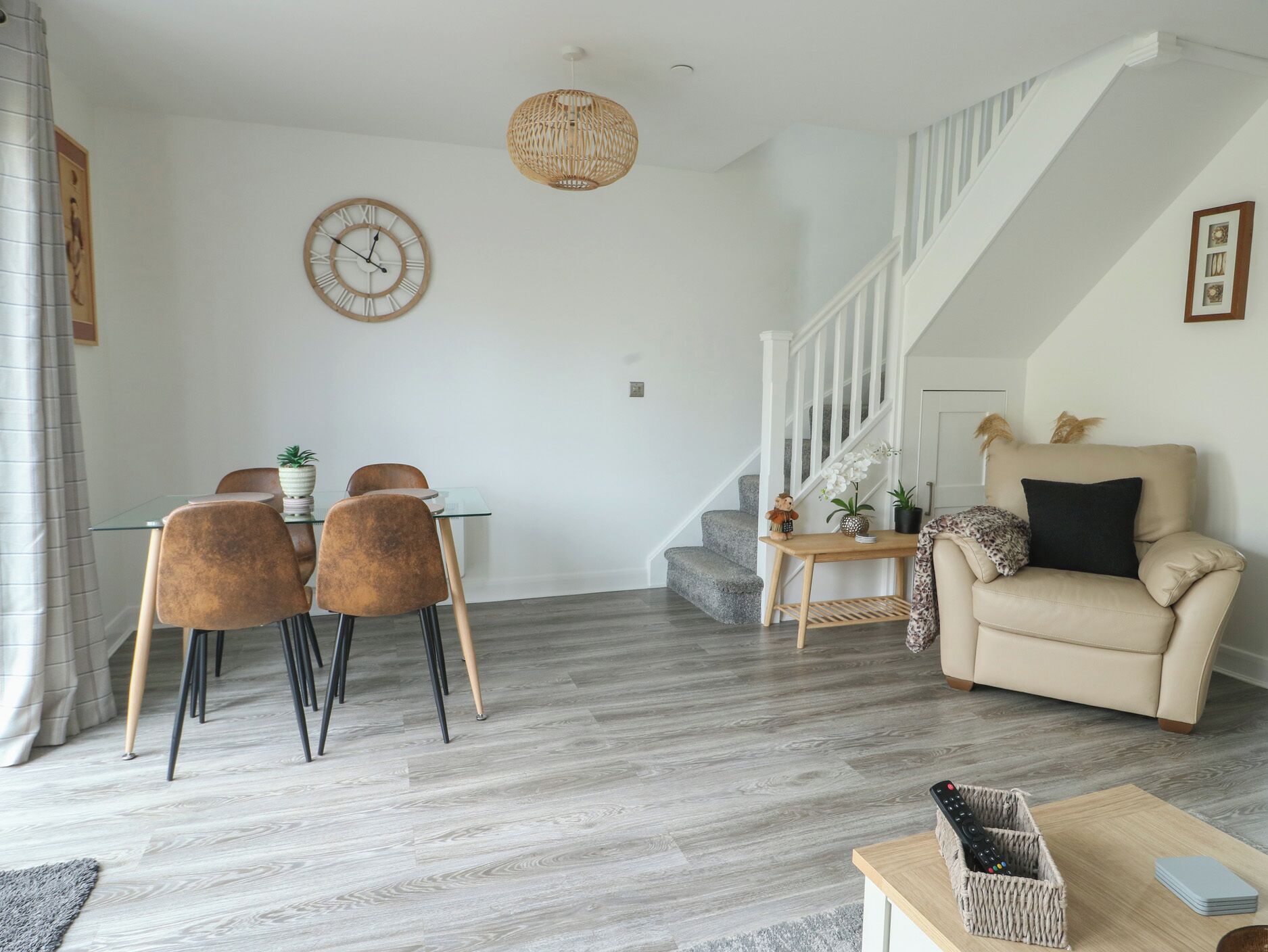 Ein modernes Wohnzimmer mit Essbereich, Treppe und einer Couch.