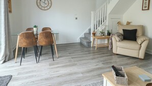 A modern living room with a dining area, a staircase, and a sofa. - 4 Parc Delfryn (Brynteg)