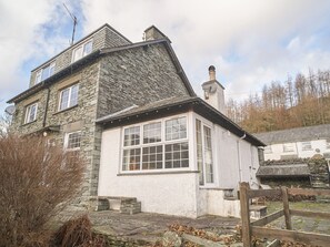 A stone house with a white exterior, a large window, and a chimney. - Plumblands (Ambleside)