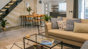 Un salon moderne comprenant un canapé, une table basse et un coin repas avec des chaises et une table.