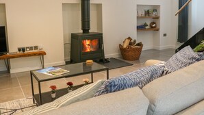 Un salon avec un poêle à bois, un canapé, une table basse et une bibliothèque.