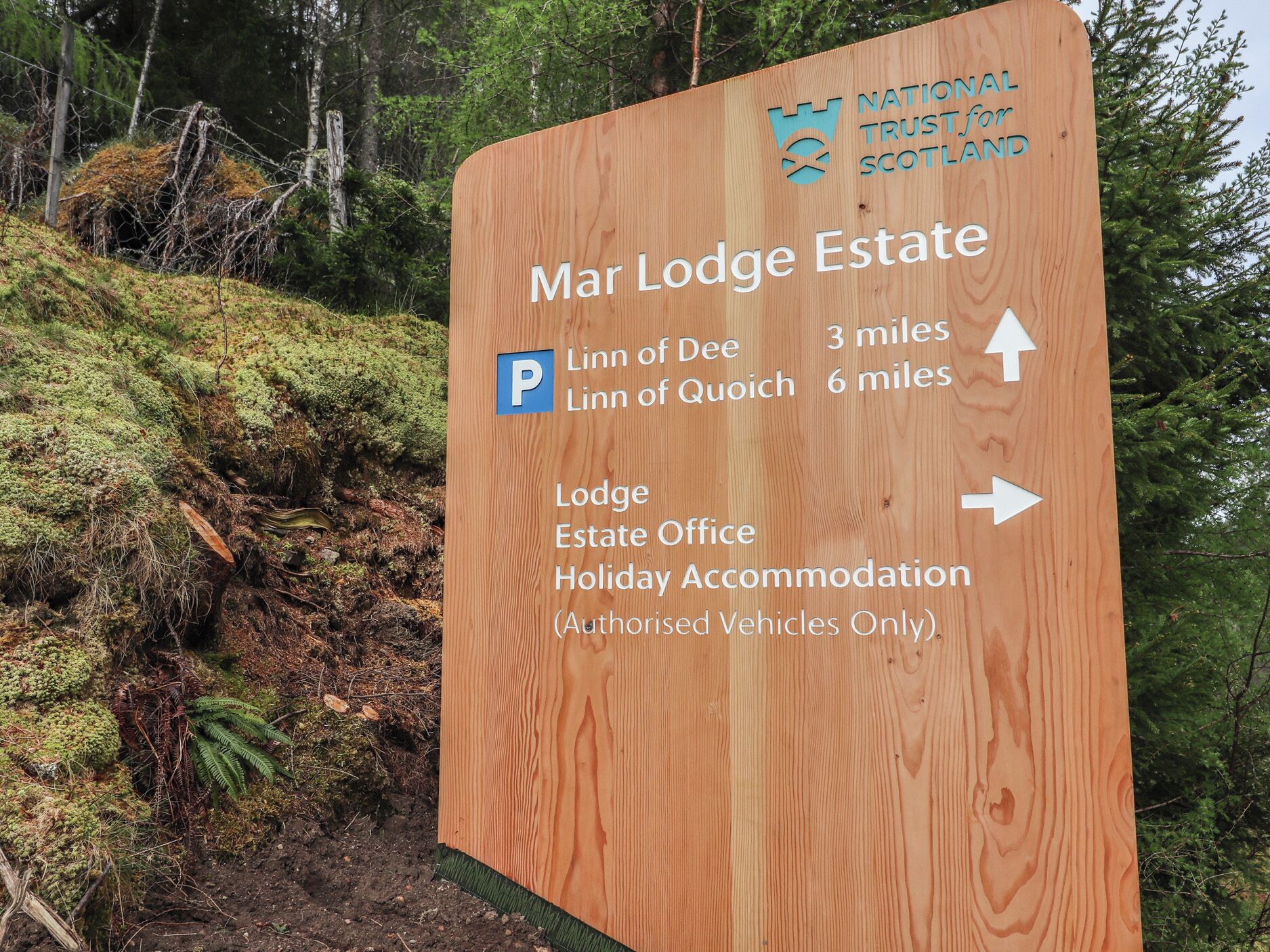 A wooden sign for Mar Lodge Estate with directions to Linn of Dee and Linn of Quoich, and mentions a Lodge, Estate Office, and Holiday Accommodation for authorized vehicles.