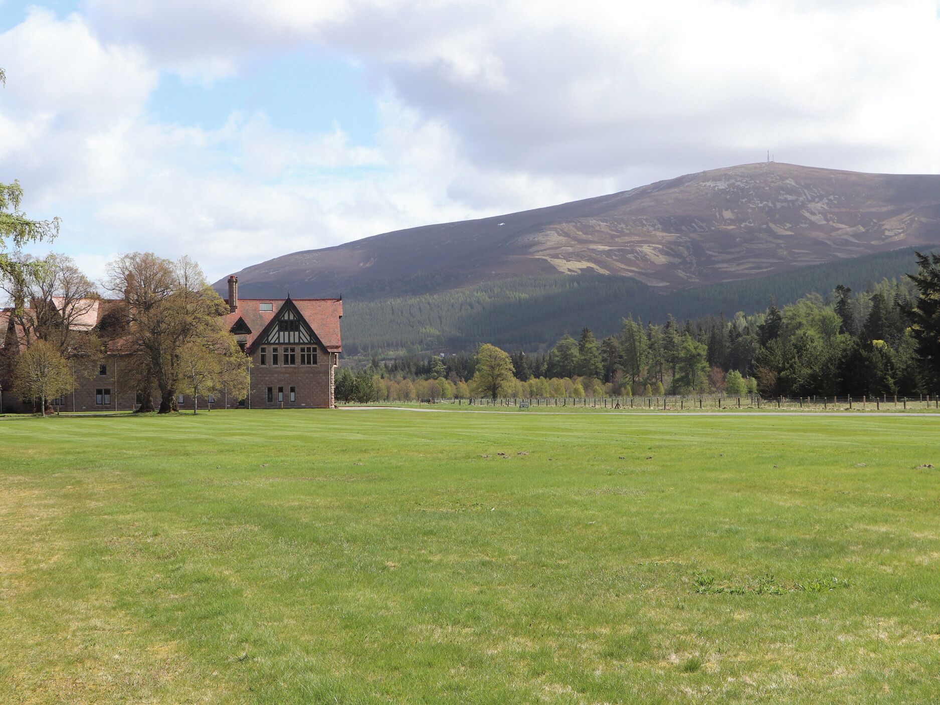 A large building with a prominent tower, surrounded by a grassy field and trees.