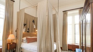 A four-poster canopy bed with a floral-patterned carpet, a bedside table with a lamp, and a large mirror. - Derry - Mar Lodge Estate (Ballater)