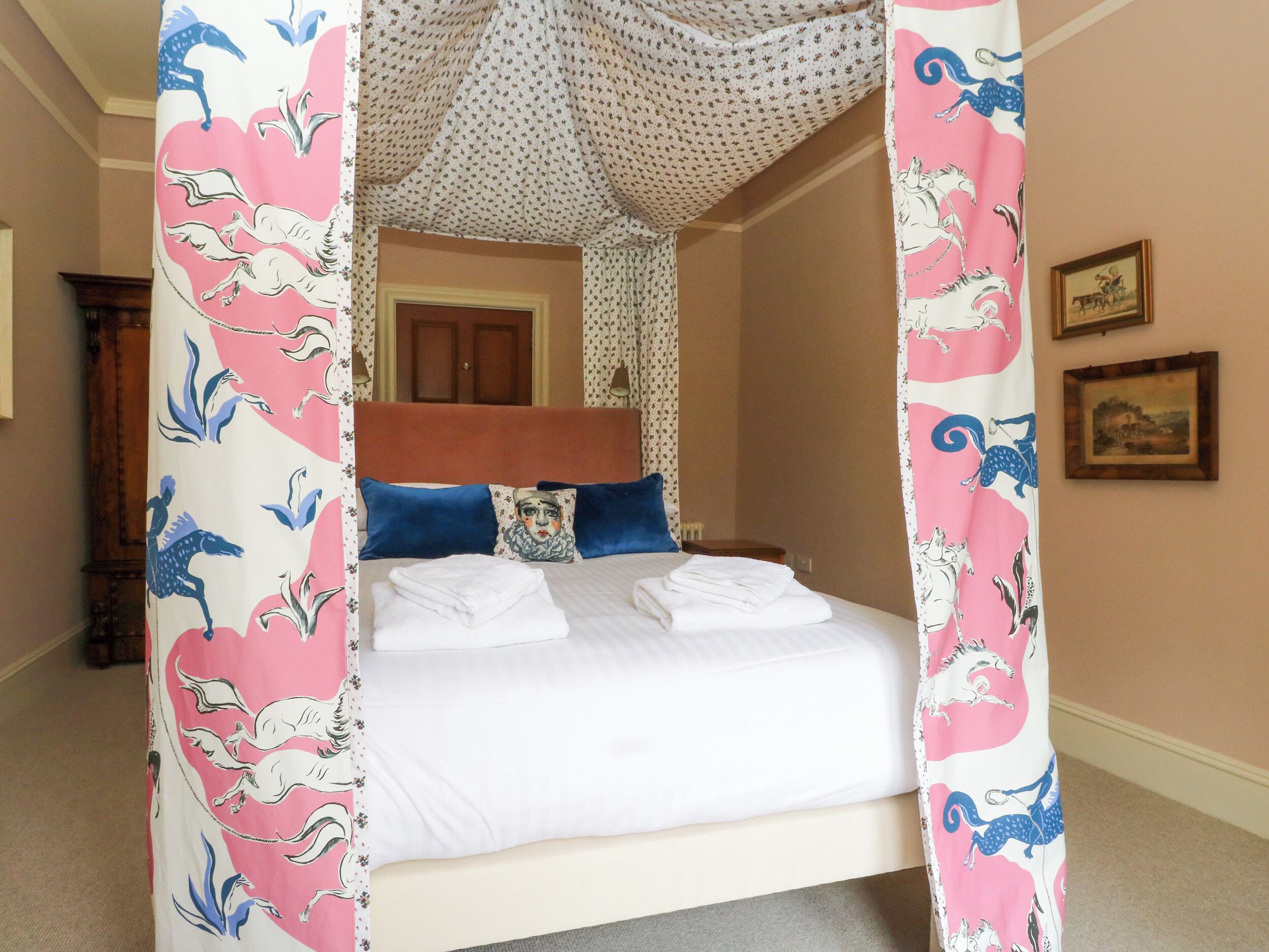 Une chambre à coucher avec un lit à baldaquin, une tête de lit en bois et un rideau à motifs floraux.