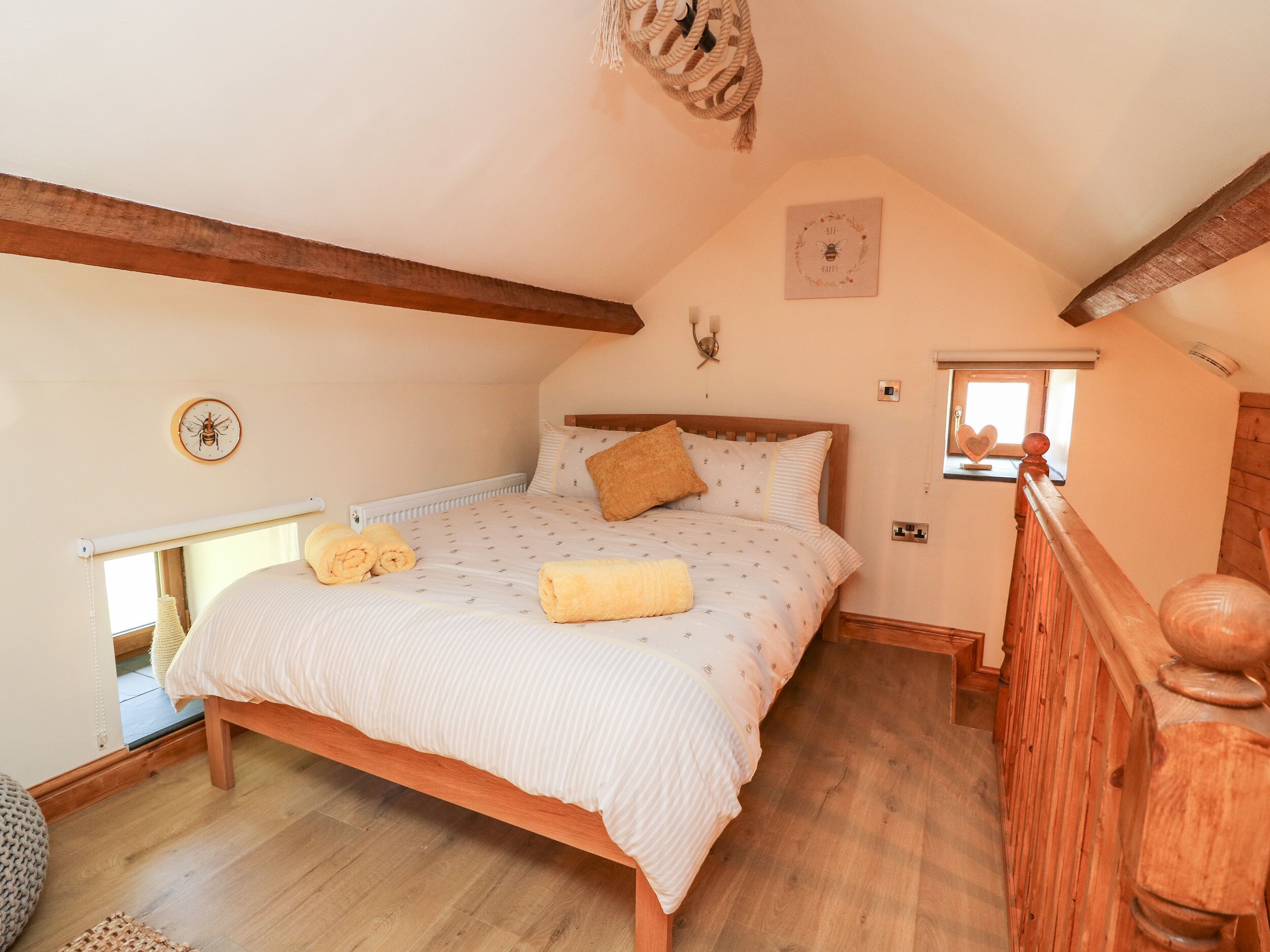 Un dormitorio acogedor con una cama de madera, un ventanal pequeño y un adorno en la pared.
